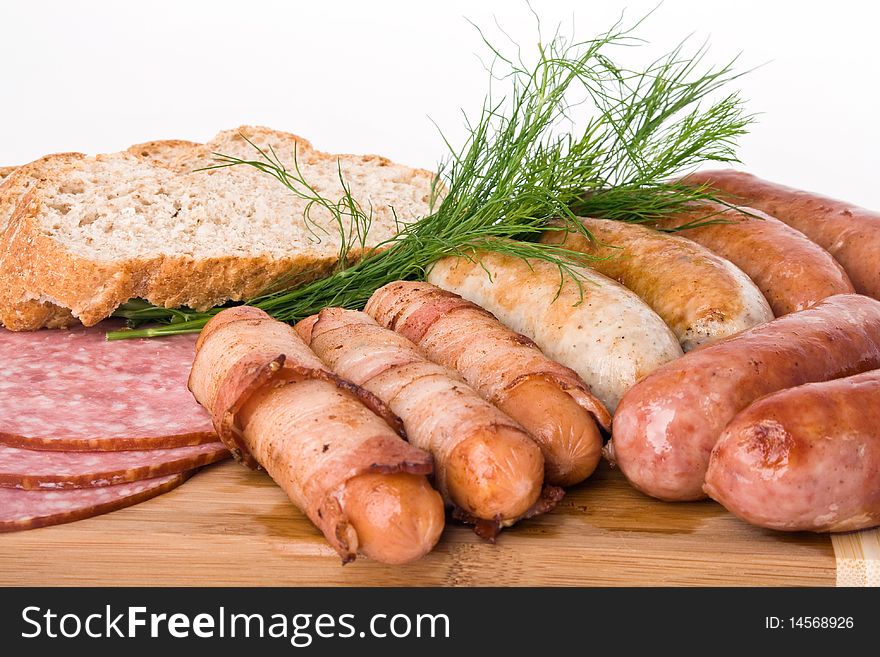 Grilled sausages on a wooden plate with bread and dill