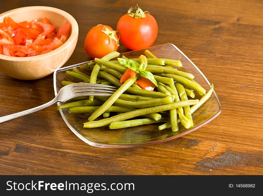 Photo of french beans on a glass platet putted on a wood table