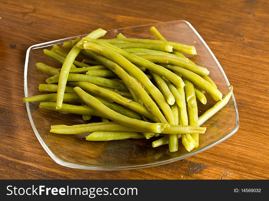 Photo of french beans on a glass platet putted on a wood table