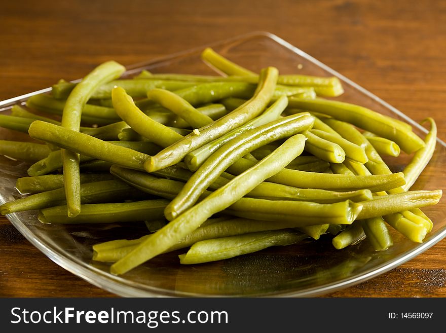 Photo of french beans on a glass platet putted on a wood table