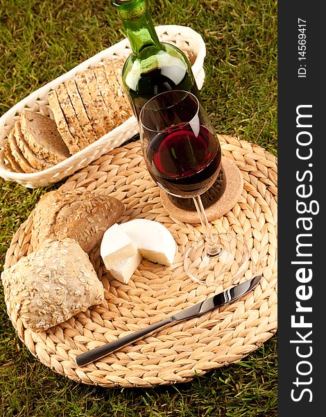 Wine picnic on grass with cheese, bread and other food.