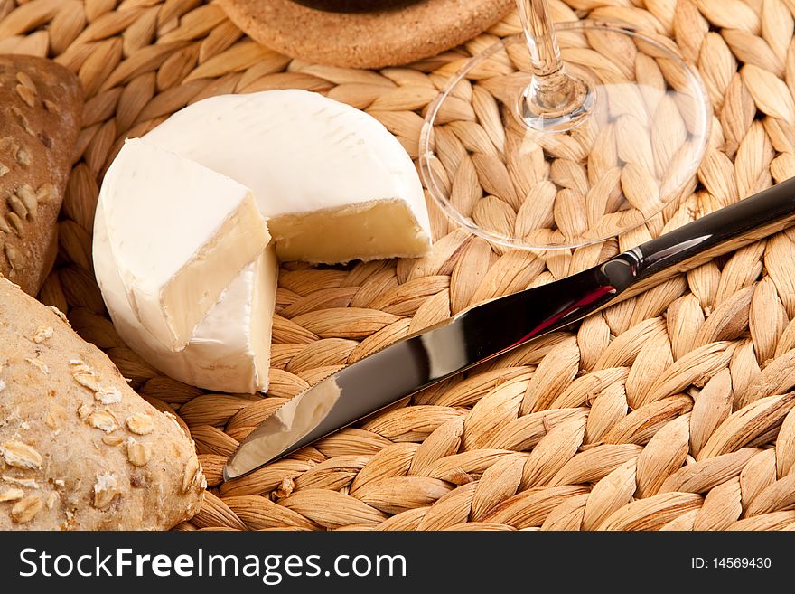 Wine picnic on grass with cheese, bread and other food.