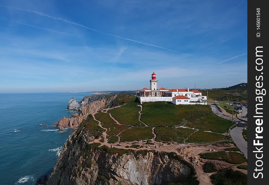 A view of a lighthouse and buildings on a cliff overlooking the ocean at Cabo da Roca, the most western tip of mainland Europe and Portugal. A view of a lighthouse and buildings on a cliff overlooking the ocean at Cabo da Roca, the most western tip of mainland Europe and Portugal.