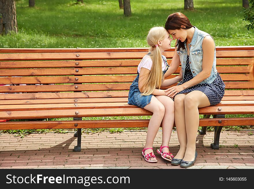 Mother and daughter sitting on a bench in a park