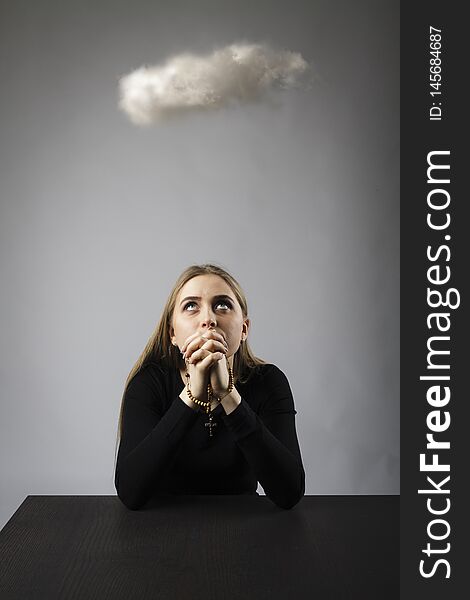 Young woman with rosary and cloud is overhead. Repentance and prayer concept. Young woman with rosary and cloud is overhead. Repentance and prayer concept