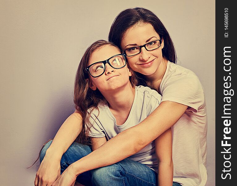 Happy relaxed casual mother and smiling kid in fashion glasses hugging on purple background with empty copy space background