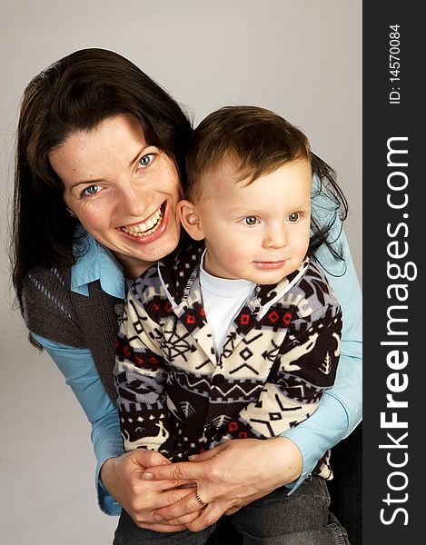 Laughing woman with son, studio shot, gray background. Laughing woman with son, studio shot, gray background