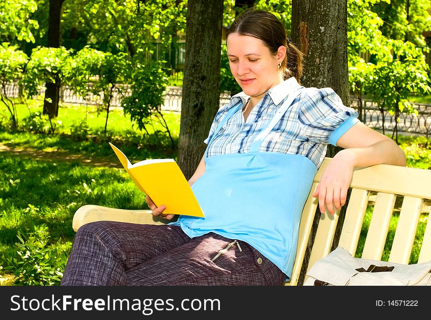 Pregnant young woman reading in park. Pregnant young woman reading in park