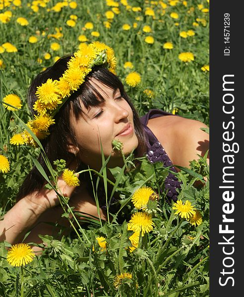 Attractive young woman smiling with a wreath of dandelions in flower meadow. Attractive young woman smiling with a wreath of dandelions in flower meadow