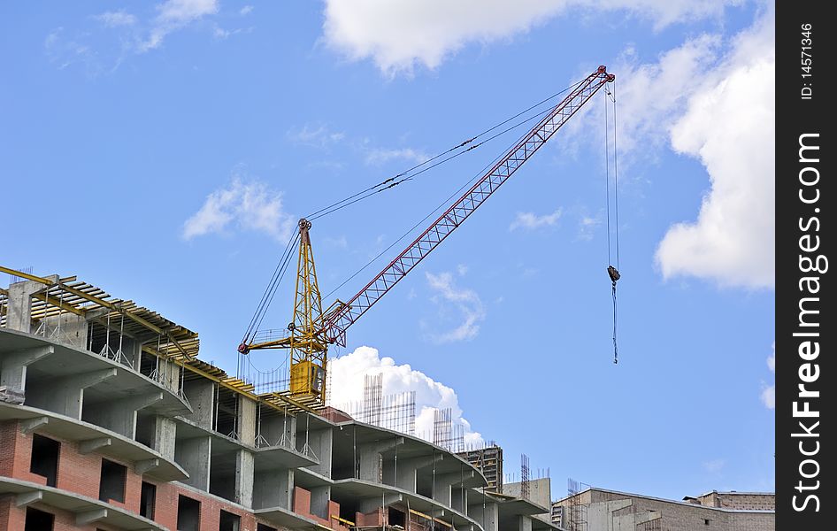Building with elevating crane and clouds on background