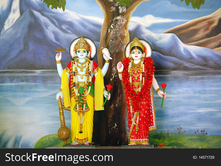 Lord Vishnu and goddess Lakshmi with hand-painted landscape background with water, rocks and mountains. Lord Vishnu and goddess Lakshmi with hand-painted landscape background with water, rocks and mountains