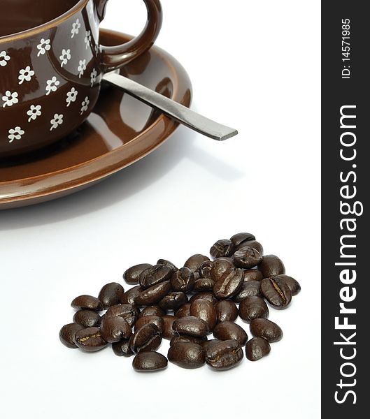 Coffee beans in foreground with cup and saucer. Coffee beans in foreground with cup and saucer