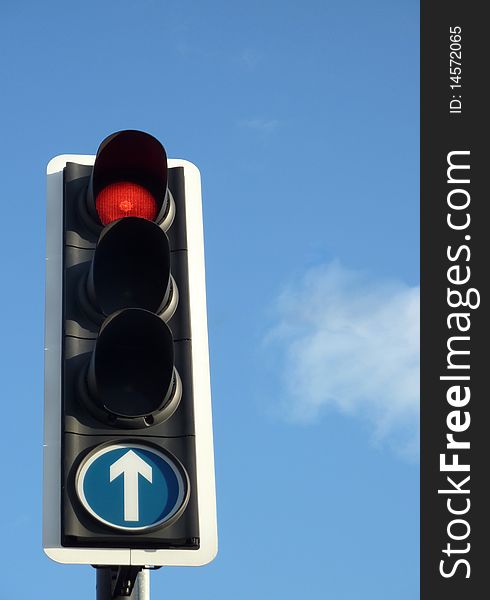 Closeup of red traffic light against blue sky