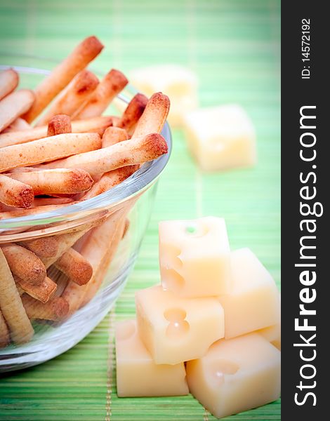 An assortment of bread sticks and cheese on a green bamboo mat. An assortment of bread sticks and cheese on a green bamboo mat