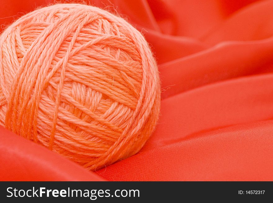 Ball of threads on a red fabric close up