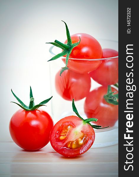 Whole and sliced cherry tomatoes in glass, on a bamboo mat. Whole and sliced cherry tomatoes in glass, on a bamboo mat.