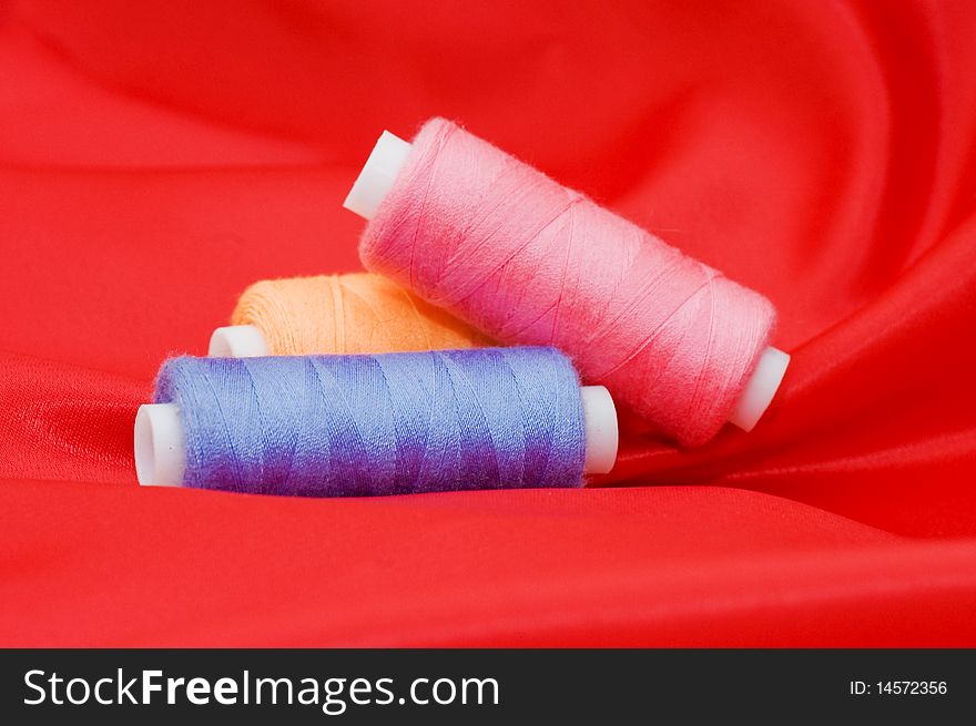 Ball of threads on a red fabric close up