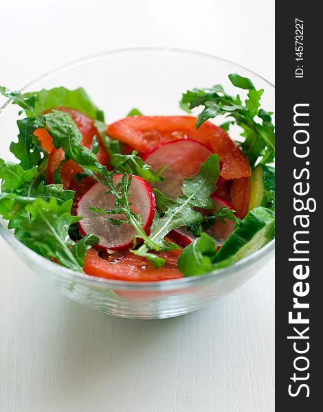 Healthy vegetable salad with tomato, radishes, cucumber, arugula and olive oil