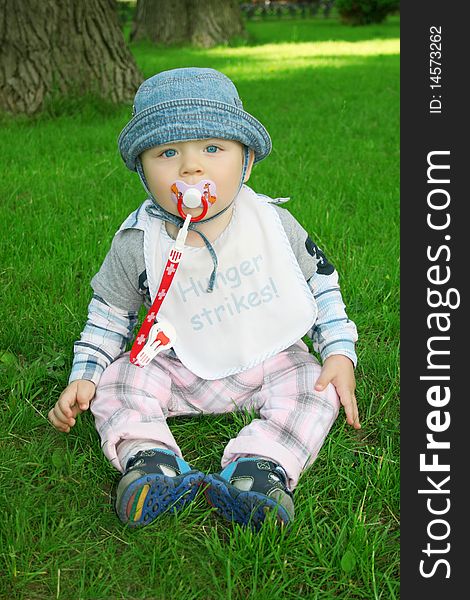 The boy the child sits on a grass in park. The boy the child sits on a grass in park