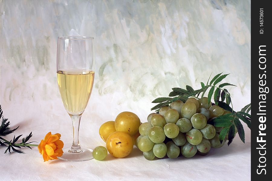 A glass of white wine with grapes isolated on painted background. A glass of white wine with grapes isolated on painted background