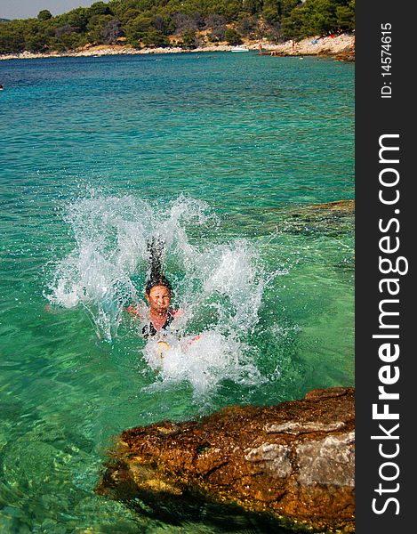 A young girl is jumping into adriatic water