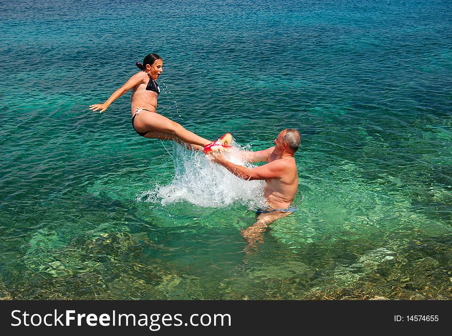 A father and his daughter are enjoying adriatic water. A father and his daughter are enjoying adriatic water