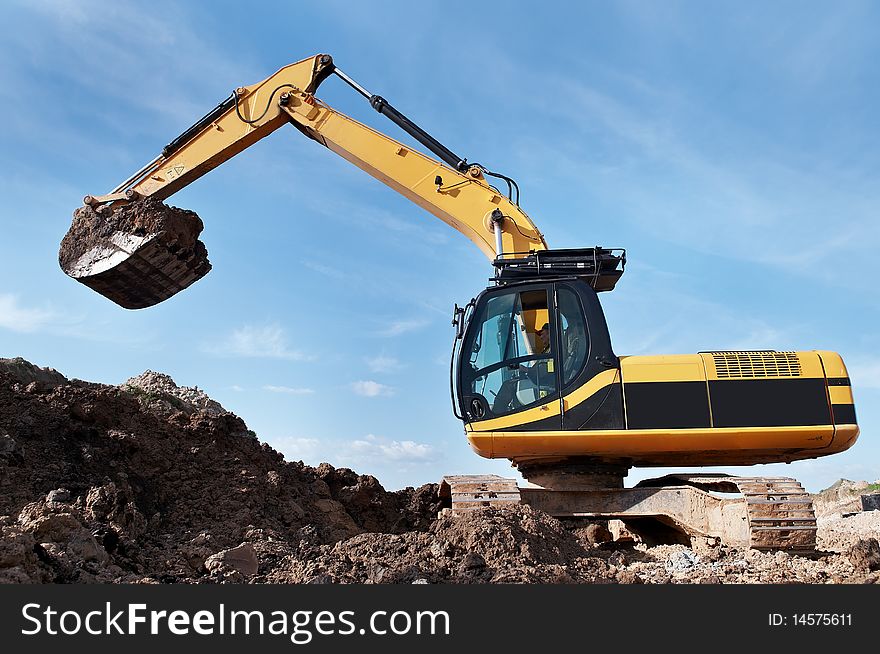 Loader Excavator standing in sandpit with risen bucket over cloudscape sky. Loader Excavator standing in sandpit with risen bucket over cloudscape sky