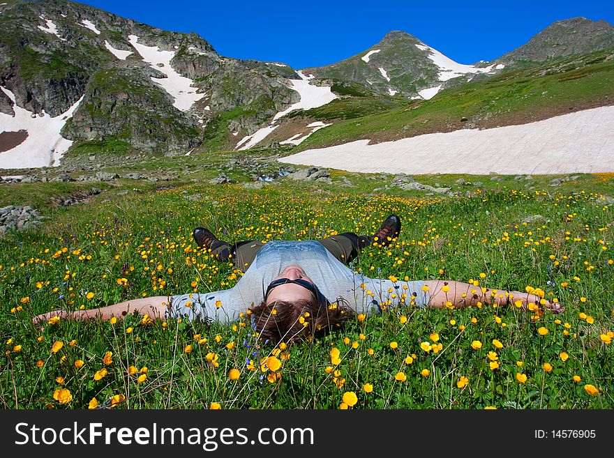 Hiker lies on meadow in mountains