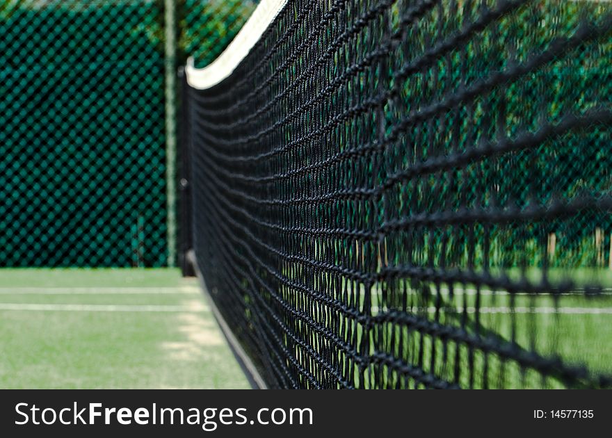 Low angle parallel shot of a tennis net on a bright day.
