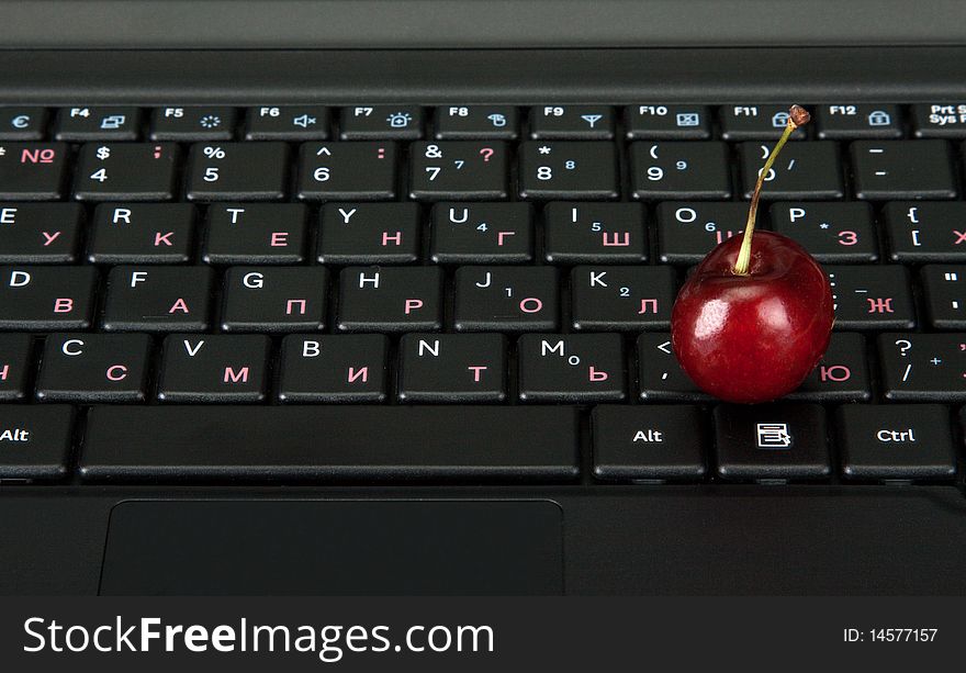 Blackenning keyboard of the computer and ripe berry to sweet cherrieses