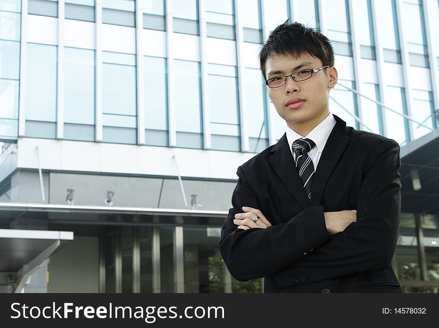 A young Asian business executive standing in front of an office building. A young Asian business executive standing in front of an office building