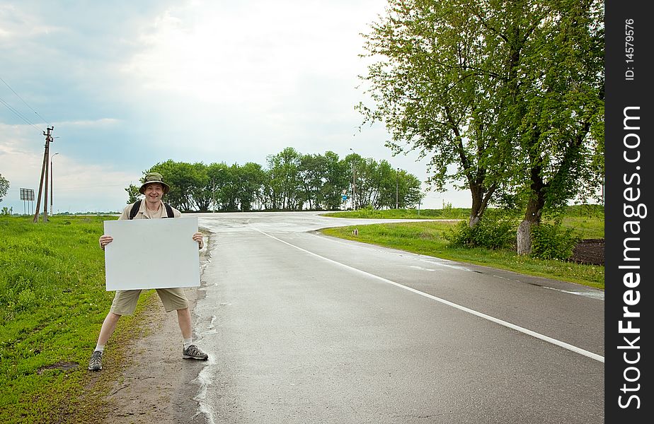 Brisk tourist with a poster on a country road. Brisk tourist with a poster on a country road