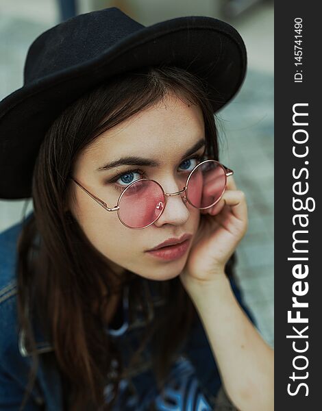 Portrait of attractive young woman in stylish glasses and hat