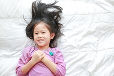 Smiling Little Asian Child Girl Lying On Bed Looking At Camera. Above View Stock Photo Smiling Little Asian Child Girl Lying On Bed Looking At Camera. Above View Stock Photo