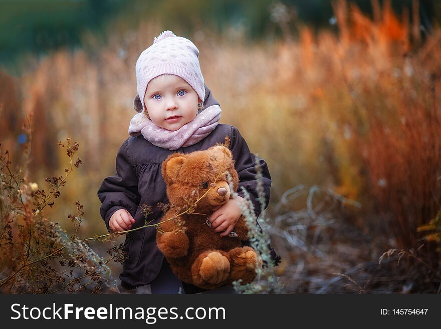 Little girl in cap and coat with Teddy bear in autumn outdoor. Little girl in cap and coat with Teddy bear in autumn outdoor