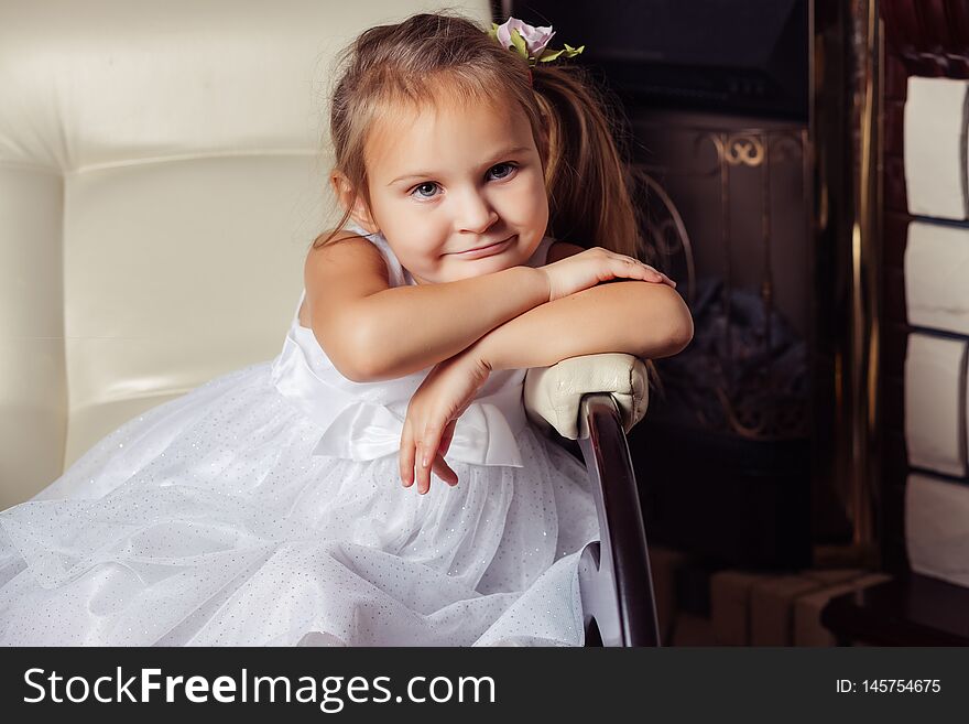 Little girl in white dress sitting on a chair. Little girl in white dress sitting on a chair