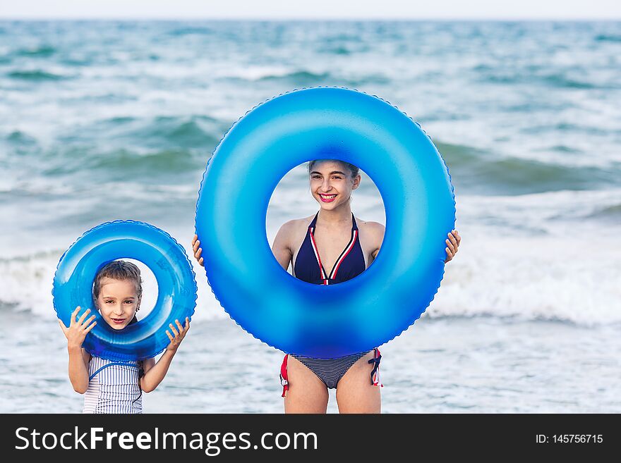 Happy Girls Hold Floating Inflatable Circles On Sea Beach.