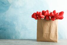 Paper Bag With Beautiful Red Tulips On Table Against Blue Background Stock Images