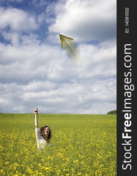 Woman in rapeseed field throwing a paper plane