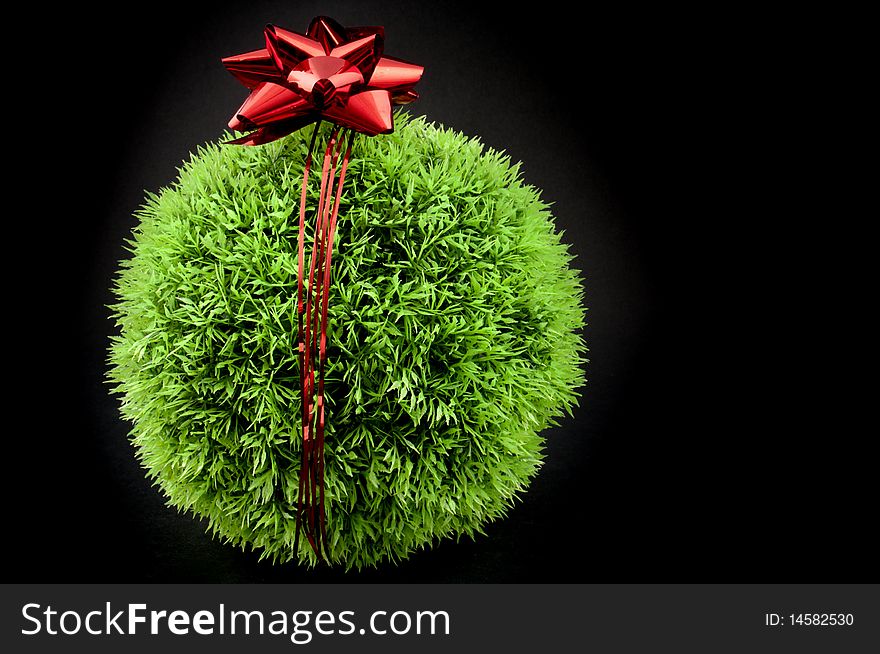 Green grass ball with red bow and ribbon over it, a gift fot the earth. Green grass ball with red bow and ribbon over it, a gift fot the earth