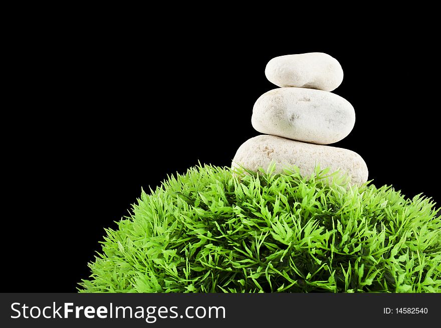 Three stones over a grass plastic ball, isolated on black. Three stones over a grass plastic ball, isolated on black
