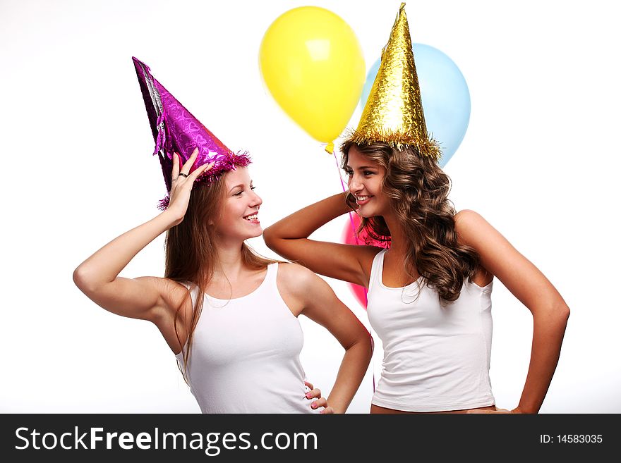 Two young girlfriends in holiday caps with color balloons. Two young girlfriends in holiday caps with color balloons