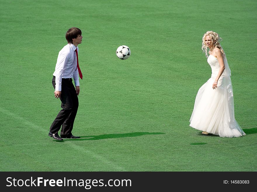 Young wedding couple playing football on the green field. Young wedding couple playing football on the green field