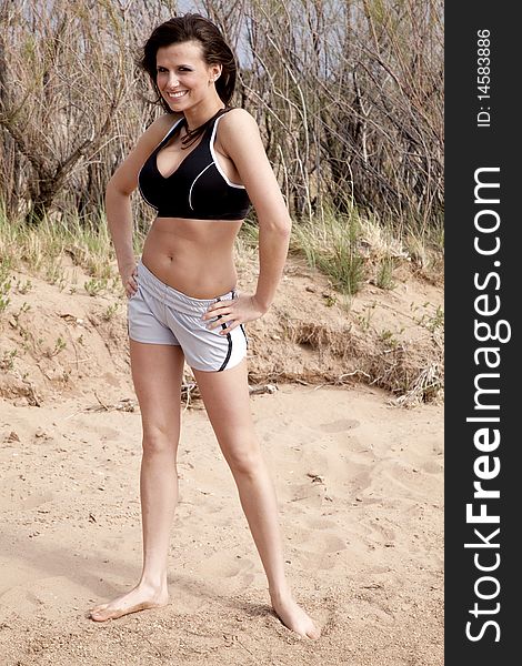 A woman in a fitness outfit in the sand. A woman in a fitness outfit in the sand.