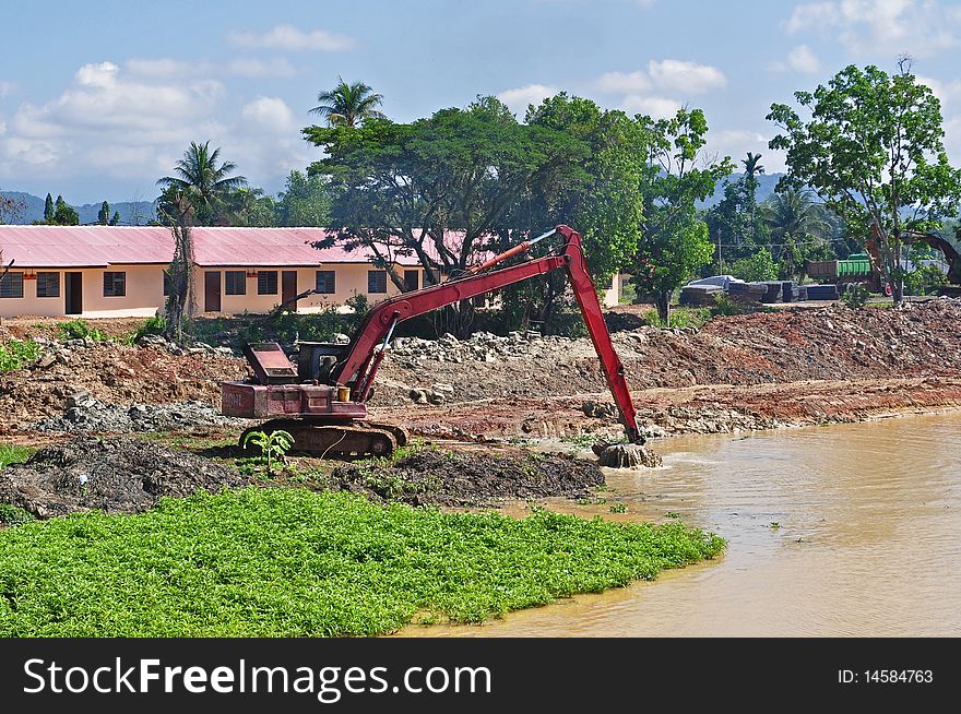 Excavator digging earth on the river side