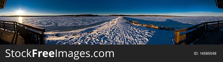 Panoramic view of sea gulf covered with ice and road to the coast