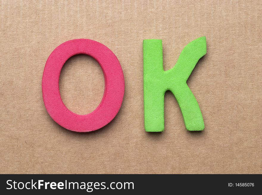 3D Plastic OK letters over cardboard background macro shot