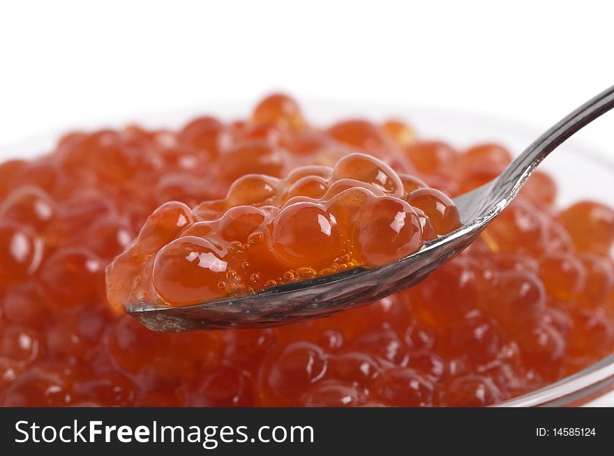 Red caviar in the little glass bow and spoon fragment isolated over white background