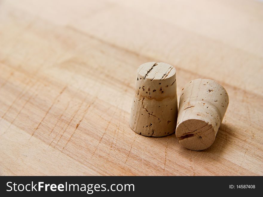 Two wine corks isolated on a wooden board.