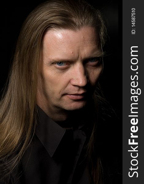 Portrait of serious man with long hair over a black background. Portrait of serious man with long hair over a black background
